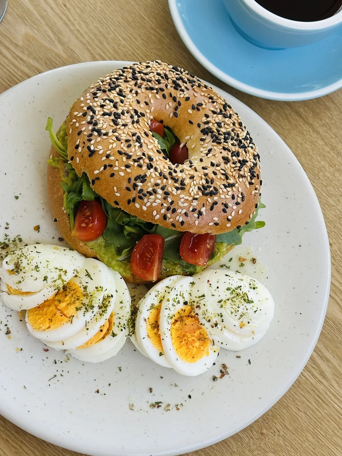 Bagel com tomate e folhas verdes, servido com ovos