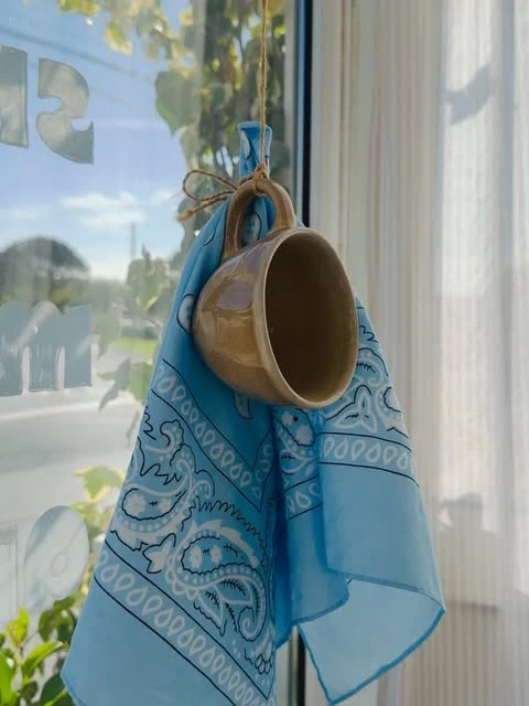 Saco azul e chávena junto à janela